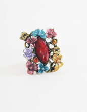 Koperkleurige ring met rode steen en een bloemenrand